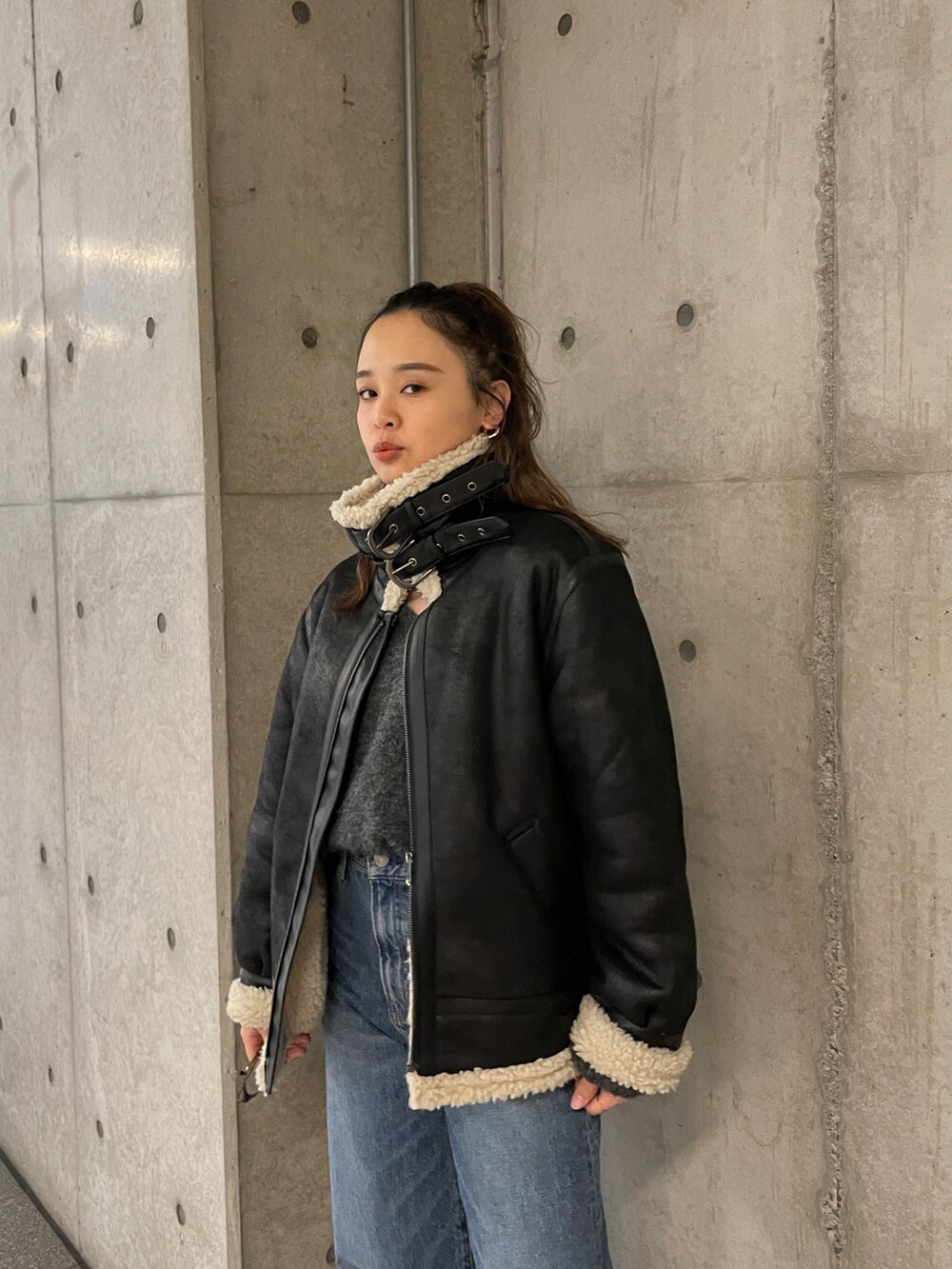 ブラック系のムートンコート、ブルー系のデニムパンツ、グレー系のニット/セーターを着用したレディースの冬コーディネートの2枚目の写真