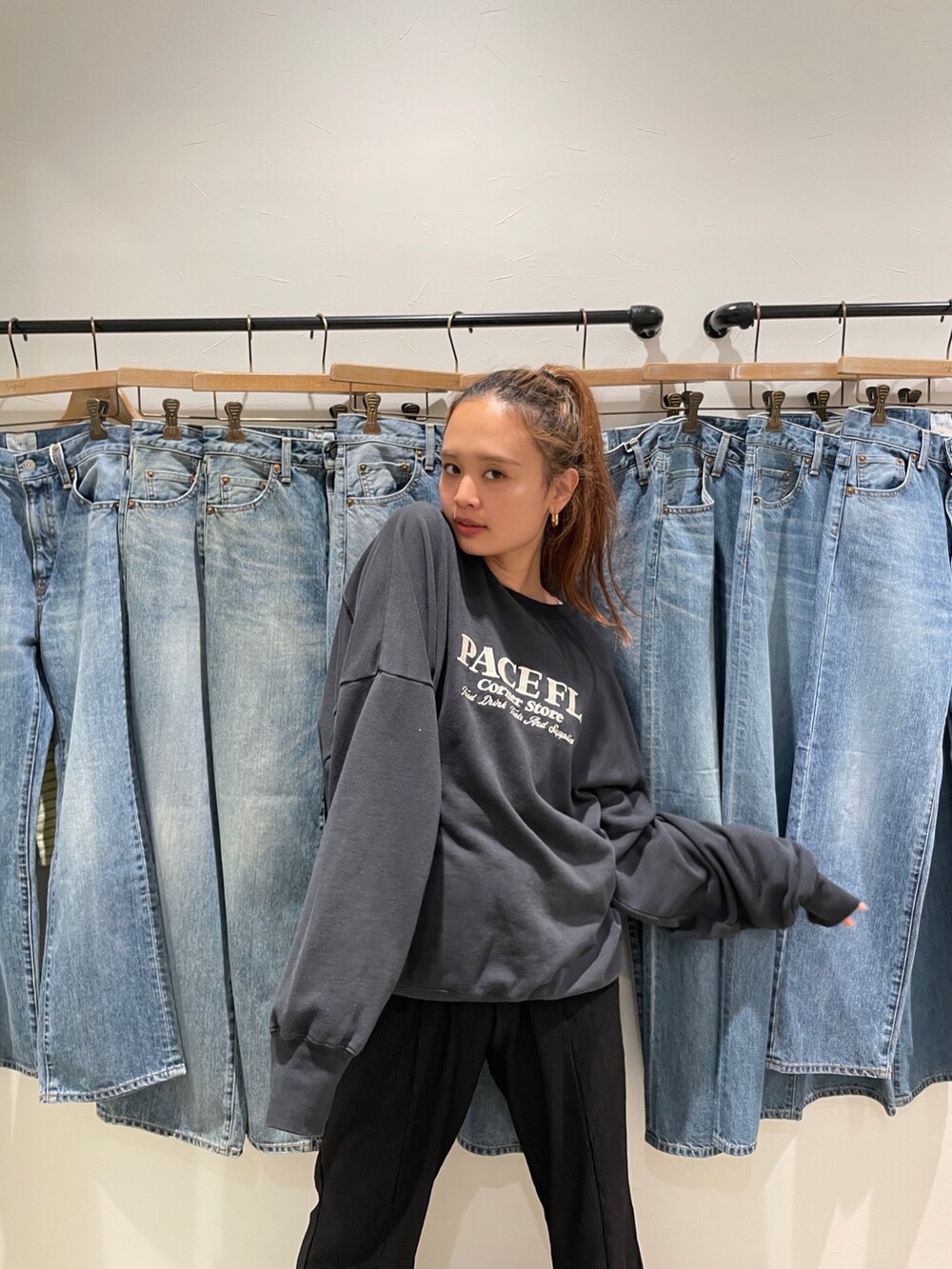 グレー系のスウェット、ブルー系のデニムパンツ、ホワイト系のスニーカーを着用したレディースの夏コーディネートの3枚目の写真