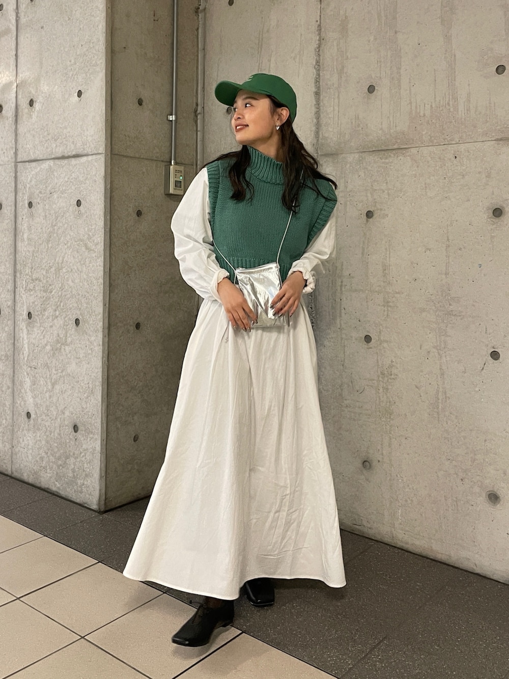 シルバー系のショルダーバッグ、グリーン系のワンピース、グリーン系のキャップを着用したレディースの冬コーディネートの2枚目の写真