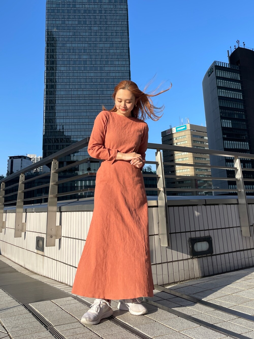 オレンジ系のワンピース、ブルー系のデニムジャケットを着用したレディースの春コーディネートの2枚目の写真