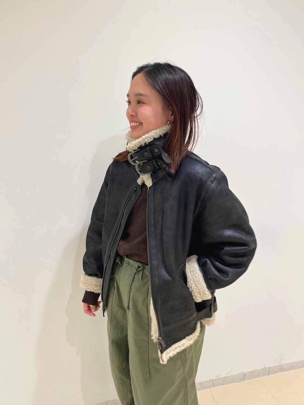 ブラウン系のムートンコート、パープル系のニット/セーター、ベージュ系のその他パンツを着用したレディースの冬コーディネートの2枚目の写真