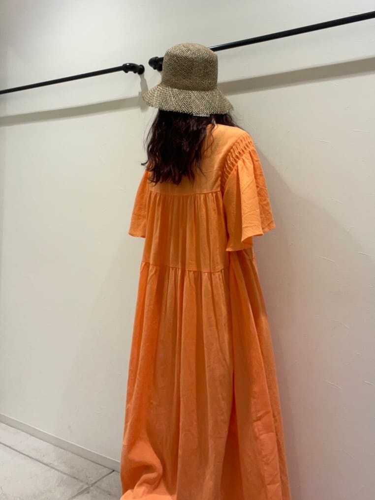 オレンジ系のワンピース、ベージュ系のハットを着用したレディースの春コーディネートの7枚目の写真