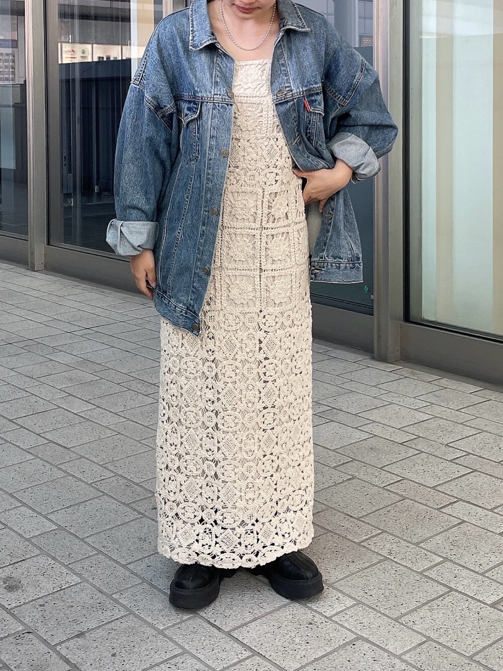 ブルー系のデニムジャケット、ベージュ系のワンピースを着用したレディースの春コーディネートの2枚目の写真