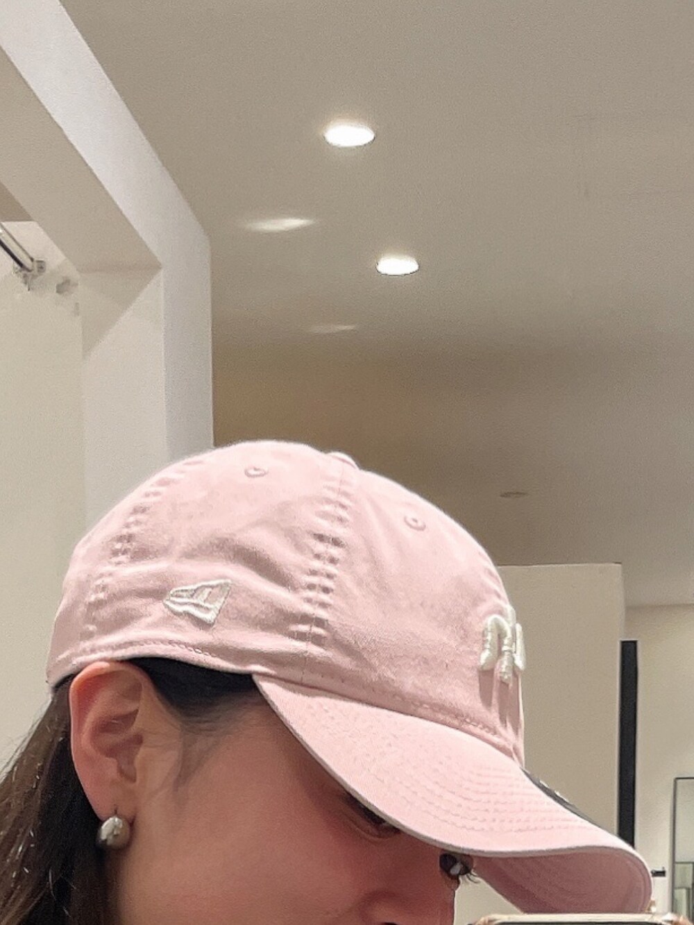 グレー系のブルゾン、ピンク系のキャップを着用したレディースの冬コーディネートの2枚目の写真