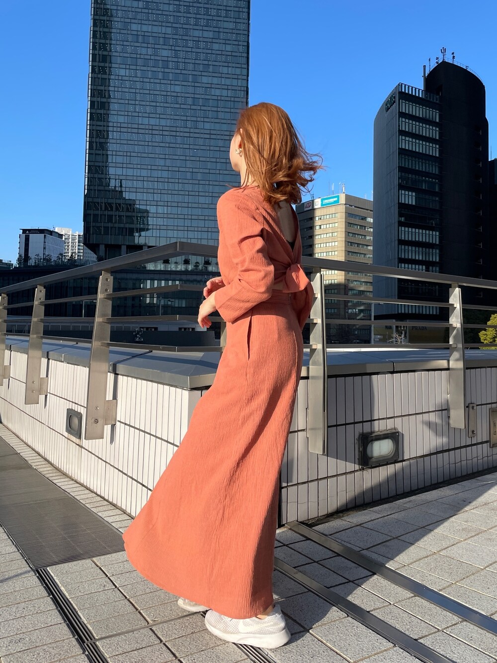 オレンジ系のワンピース、ブルー系のデニムジャケットを着用したレディースの春コーディネートの3枚目の写真