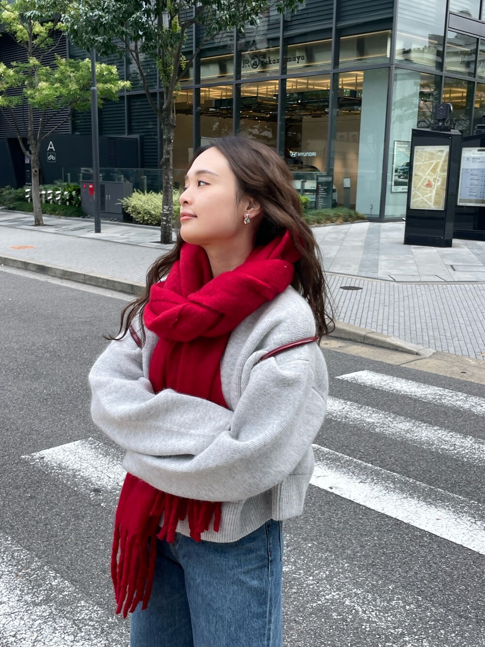 ブルー系のデニムパンツ、レッド系のハンドバッグ、グレー系のカーディガン/ボレロを着用したレディースの秋コーディネートの6枚目の写真