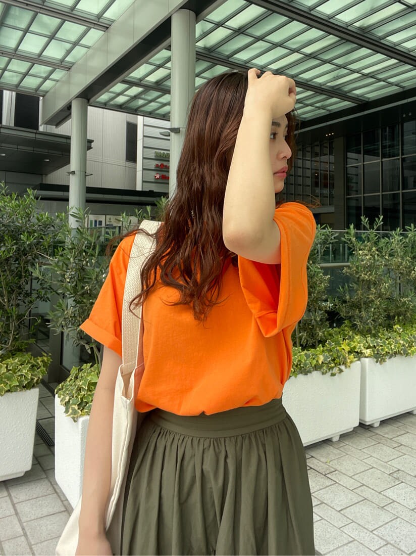 ベージュ系のスカート、オレンジ系のTシャツ/カットソー、グリーン系のハンドバッグを着用したレディースの春コーディネートの3枚目の写真