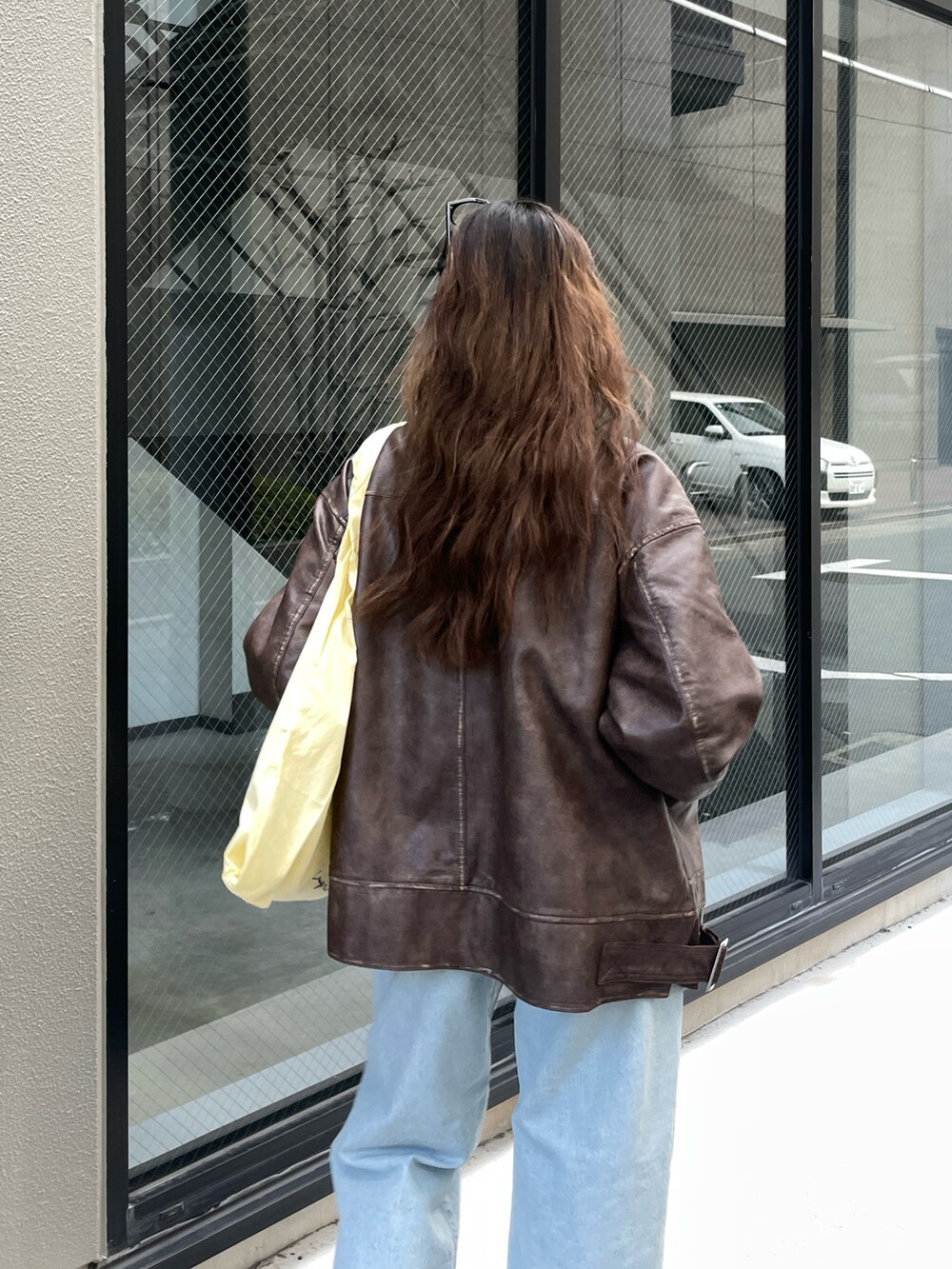 ブラウン系のブルゾン、ブルー系のデニムパンツ、イエロー系のエコバッグ/サブバッグを着用したレディースの冬コーディネートの4枚目の写真