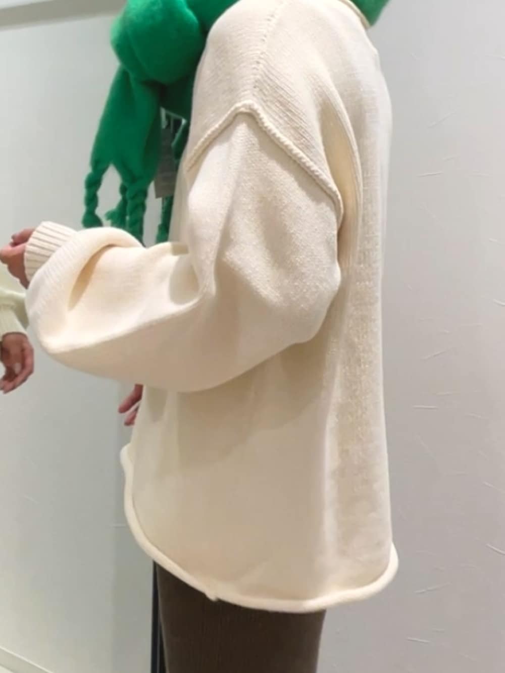 グレー系のスカート、ホワイト系のニット/セーター、グリーン系のマフラーを着用したレディースの冬コーディネートの3枚目の写真