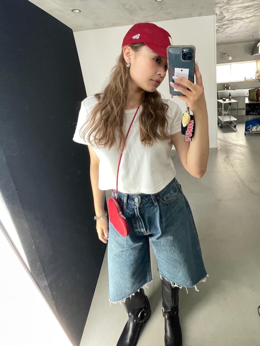 ブルー系のデニムパンツ、レッド系のショルダーバッグ、ブラック系のTシャツ/カットソーを着用したレディースの夏コーディネートの3枚目の写真