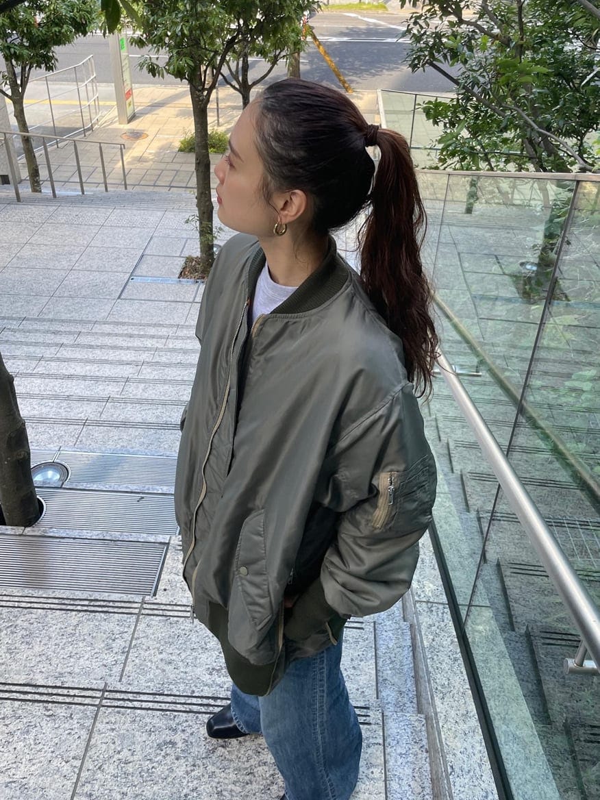 ブルー系のデニムパンツ、ブラック系のブーツ、グリーン系のMA-1を着用したレディースの秋コーディネートの2枚目の写真