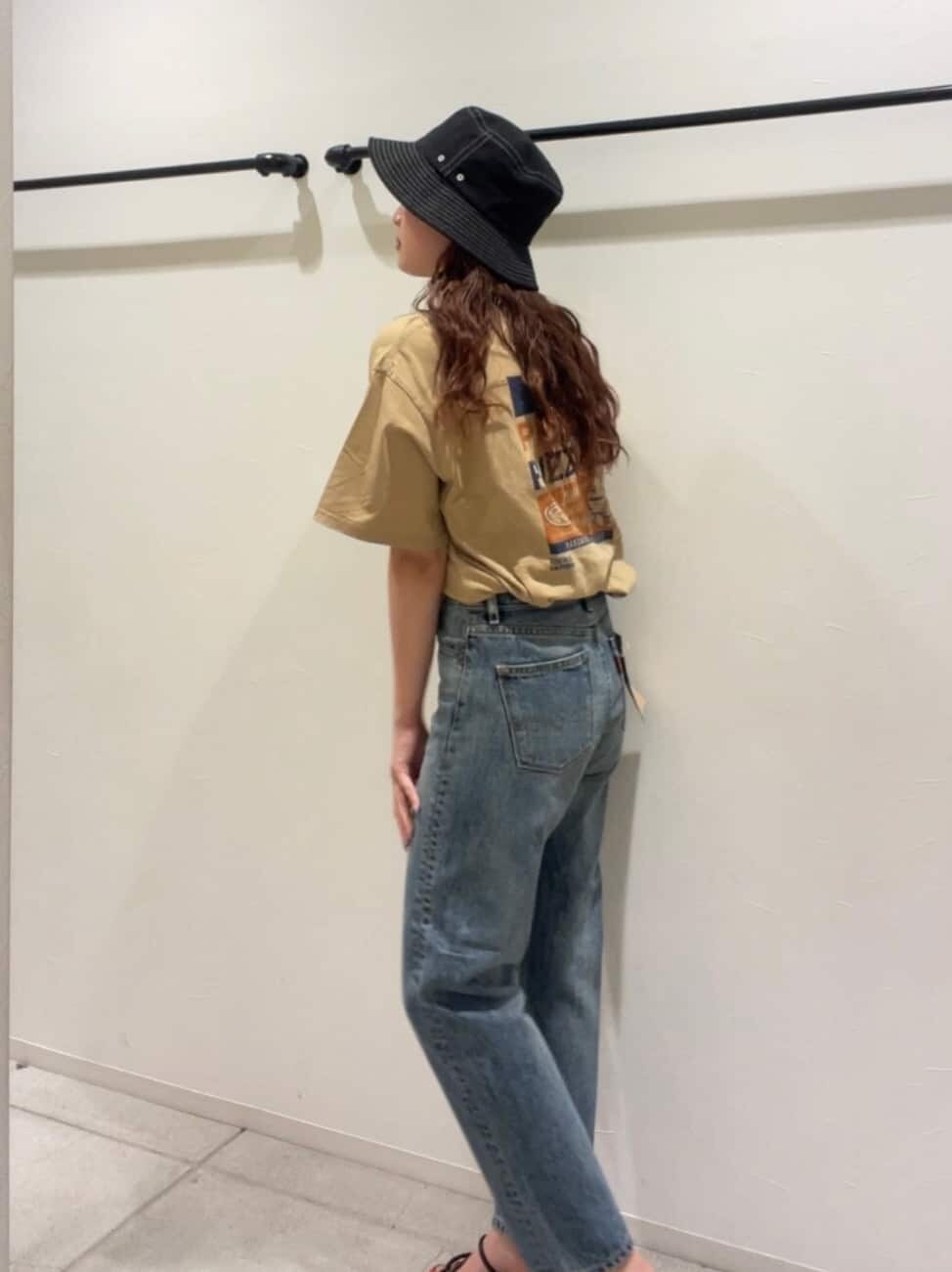 ブルー系のデニムパンツ、ブラック系のサンダル、ベージュ系のTシャツ/カットソーを着用したレディースの夏コーディネートの4枚目の写真