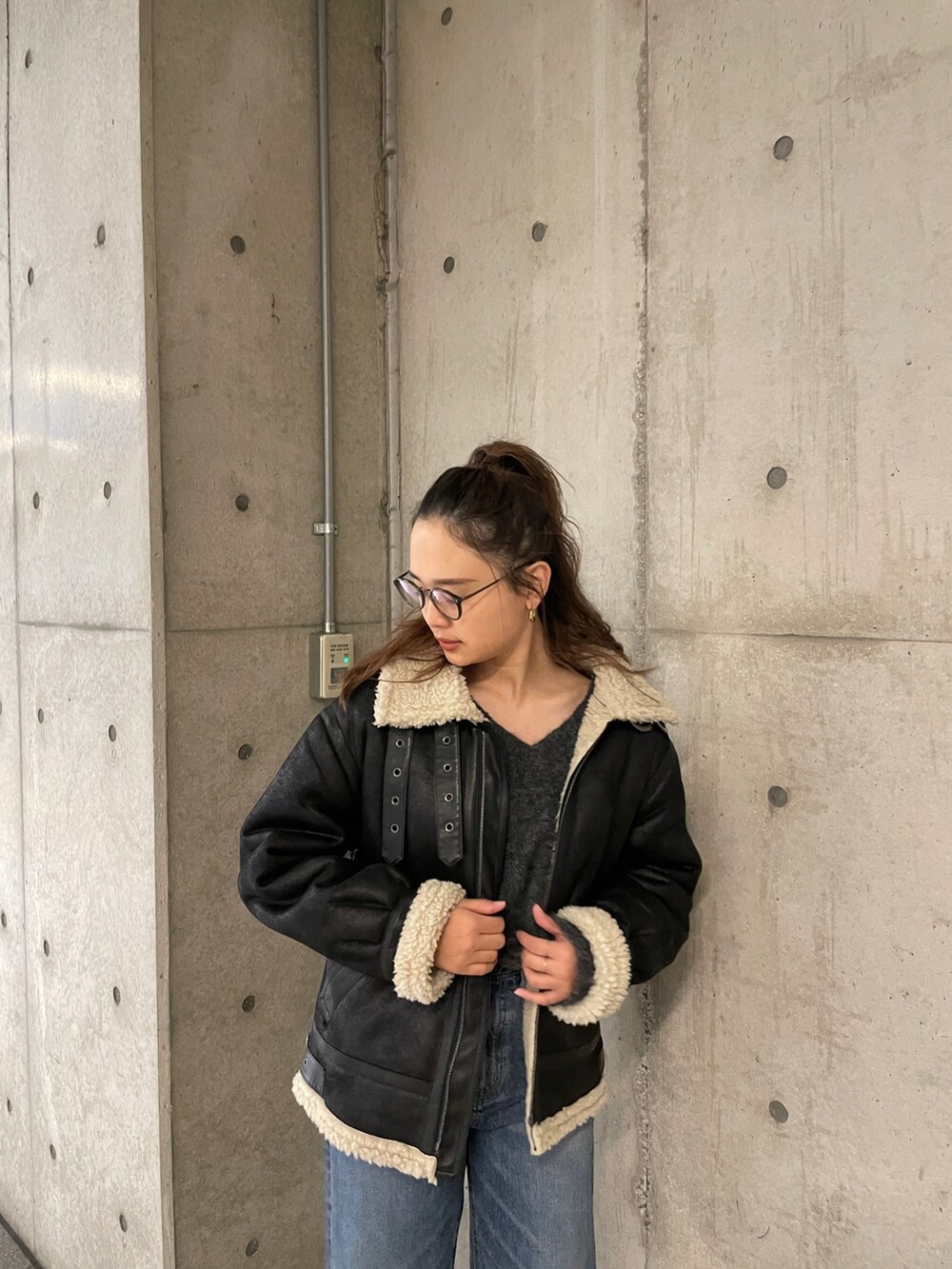 ブラック系のムートンコート、ブルー系のデニムパンツ、グレー系のニット/セーターを着用したレディースの冬コーディネートの7枚目の写真