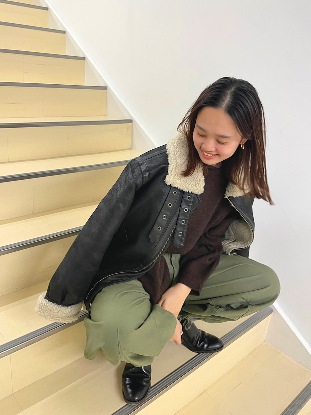 ブラウン系のムートンコート、パープル系のニット/セーター、ベージュ系のその他パンツを着用したレディースの冬コーディネートの5枚目の写真