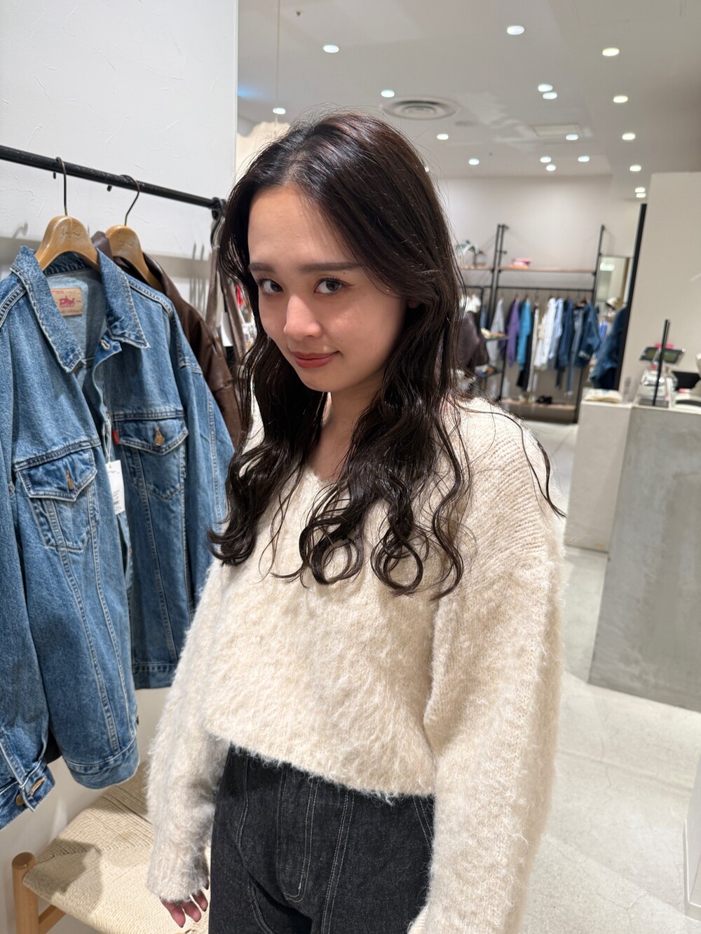 ホワイト系のニット/セーター、ブラック系のデニムパンツを着用したレディースの秋コーディネートの3枚目の写真