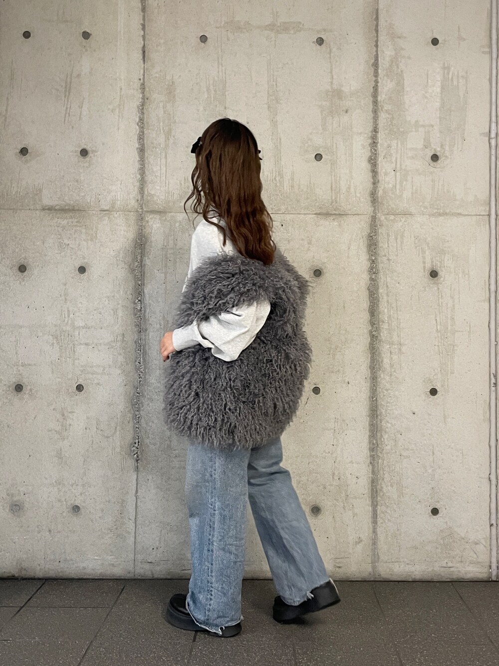 ブルー系のデニムパンツ、グレー系のスウェット、グレー系のベストを着用したレディースの冬コーディネートの5枚目の写真