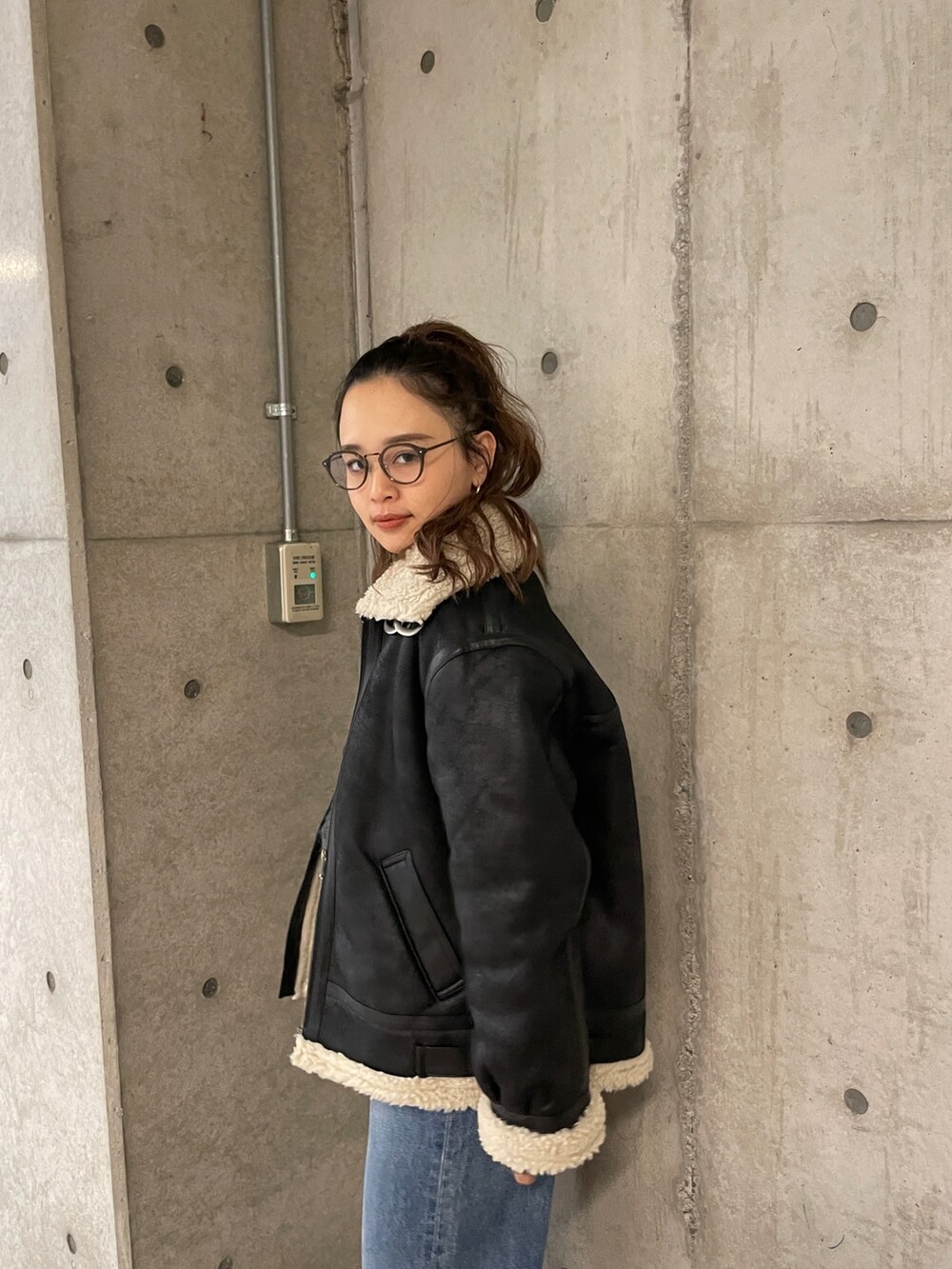 ブラック系のムートンコート、ブルー系のデニムパンツ、グレー系のニット/セーターを着用したレディースの冬コーディネートの6枚目の写真