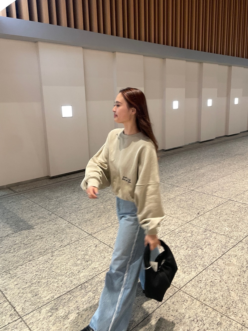 ベージュ系のスウェット、ブルー系のデニムパンツを着用したレディースの春コーディネートの2枚目の写真