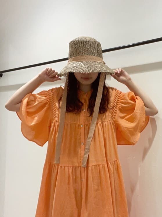 オレンジ系のワンピース、ベージュ系のハットを着用したレディースの春コーディネートの3枚目の写真