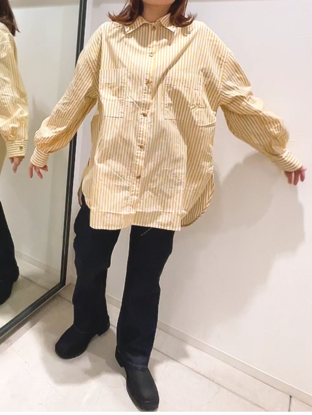 イエロー系のシャツ/ブラウス、ブルー系のデニムパンツ、ブラック系のブーツを着用したレディースの冬コーディネートの2枚目の写真