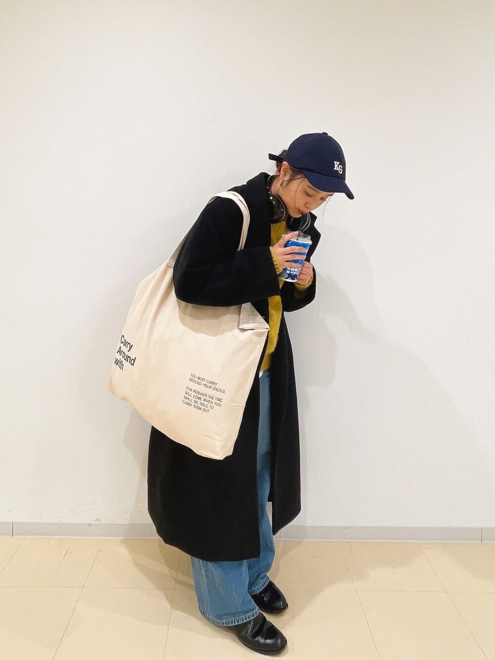 イエロー系のニット/セーター、ホワイト系のハンドバッグ、ブルー系のデニムパンツを着用したレディースの冬コーディネートの3枚目の写真