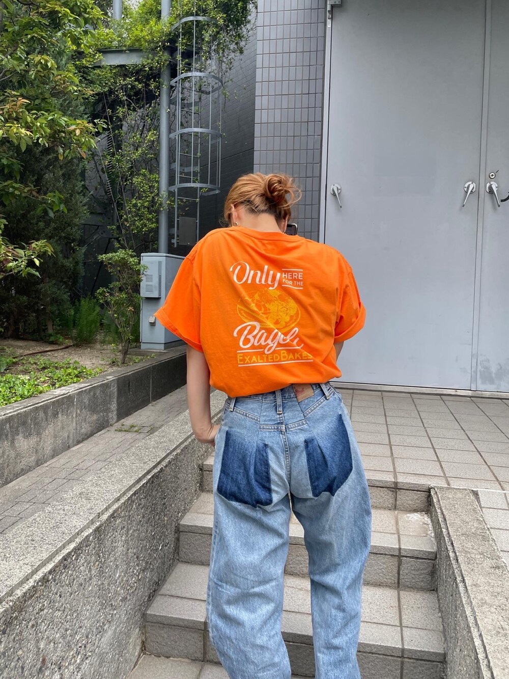 オレンジ系のTシャツ/カットソー、ブルー系のデニムパンツ、ホワイト系のスニーカーを着用したレディースの夏コーディネートの6枚目の写真