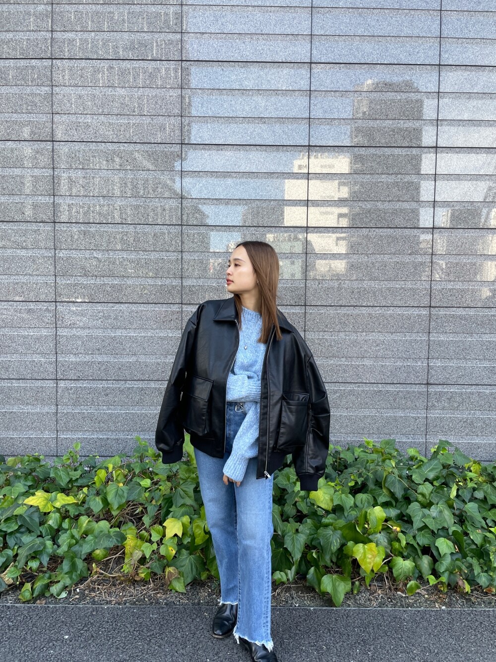 ブラック系のブルゾン、ブルー系のニット/セーター、ブルー系のデニムパンツを着用したレディースの秋コーディネートの7枚目の写真