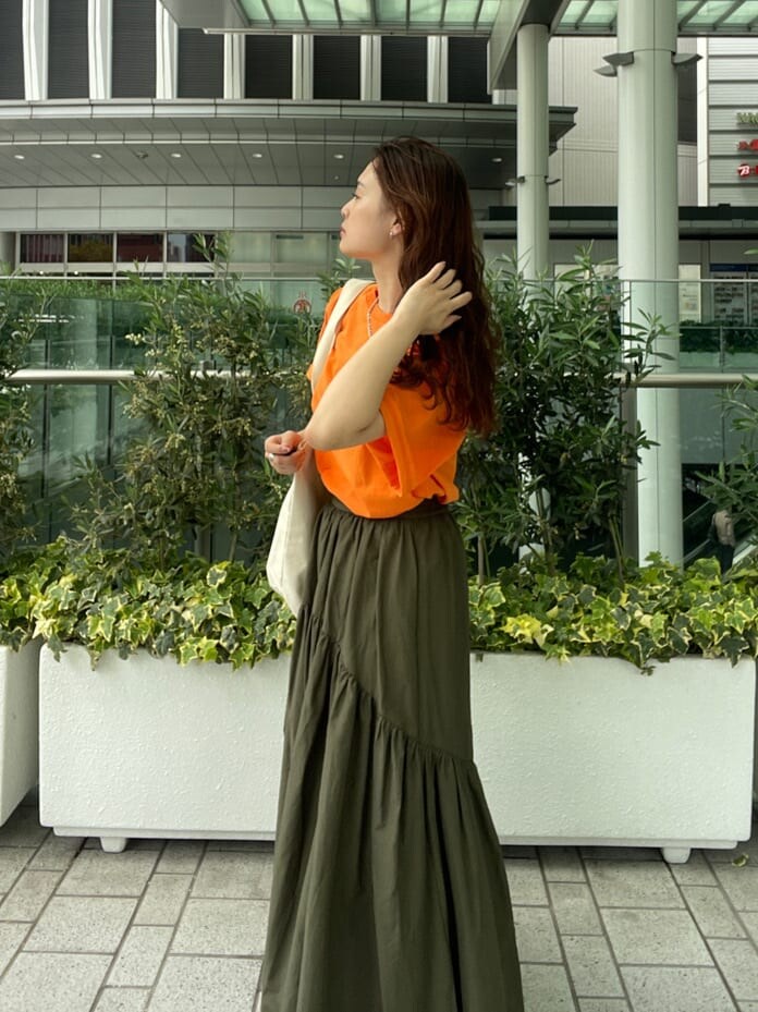 ベージュ系のスカート、オレンジ系のTシャツ/カットソー、グリーン系のハンドバッグを着用したレディースの春コーディネートの8枚目の写真