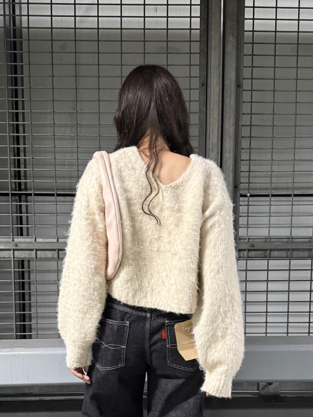 ホワイト系のニット/セーター、ブラック系のデニムパンツを着用したレディースの秋コーディネートの4枚目の写真