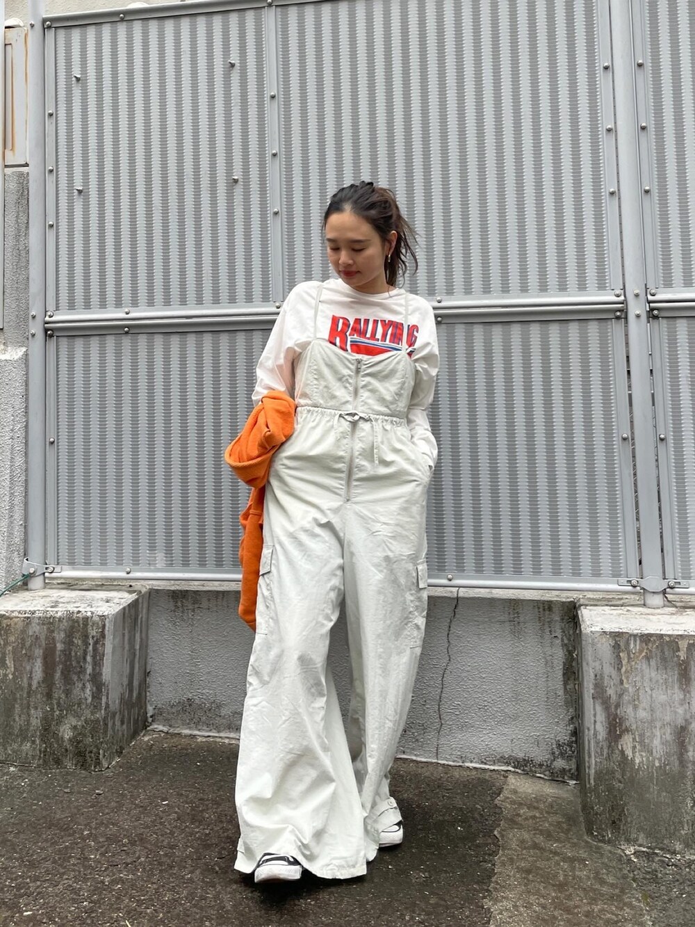 オレンジ系のカーディガン/ボレロ、ホワイト系のTシャツ/カットソー、グレー系のサロペット/オーバーオールを着用したレディースの冬コーディネートの3枚目の写真