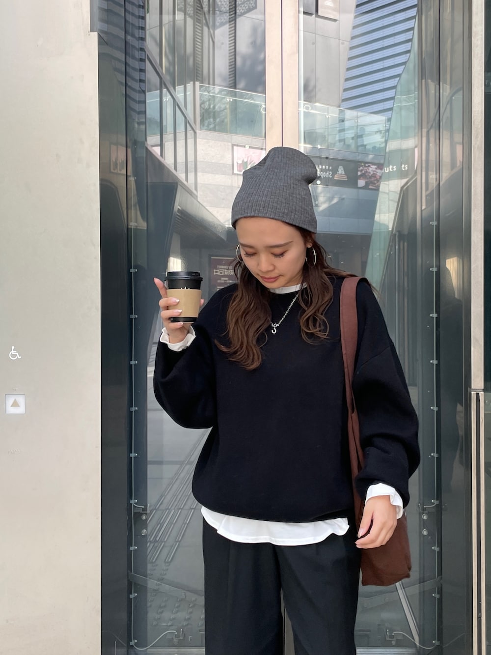 ブラック系のニット/セーター、ホワイト系のTシャツ/カットソー、ブラウン系のトートバッグを着用したレディースの冬コーディネートの5枚目の写真