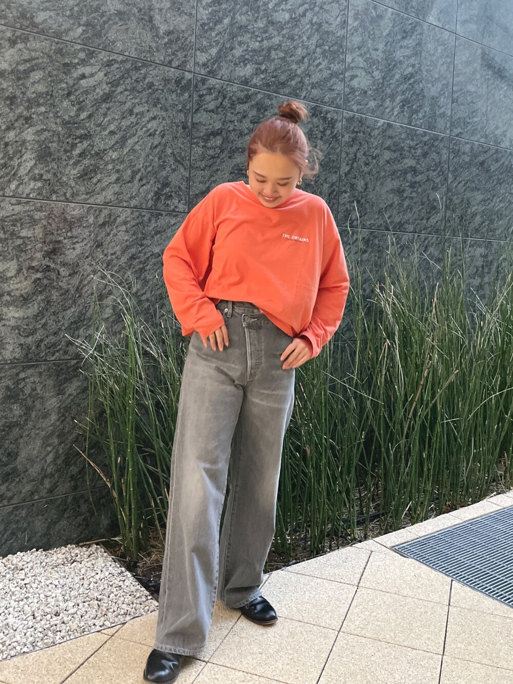 ブラック系のデニムパンツ、オレンジ系のTシャツ/カットソーを着用したレディースの冬コーディネートの2枚目の写真