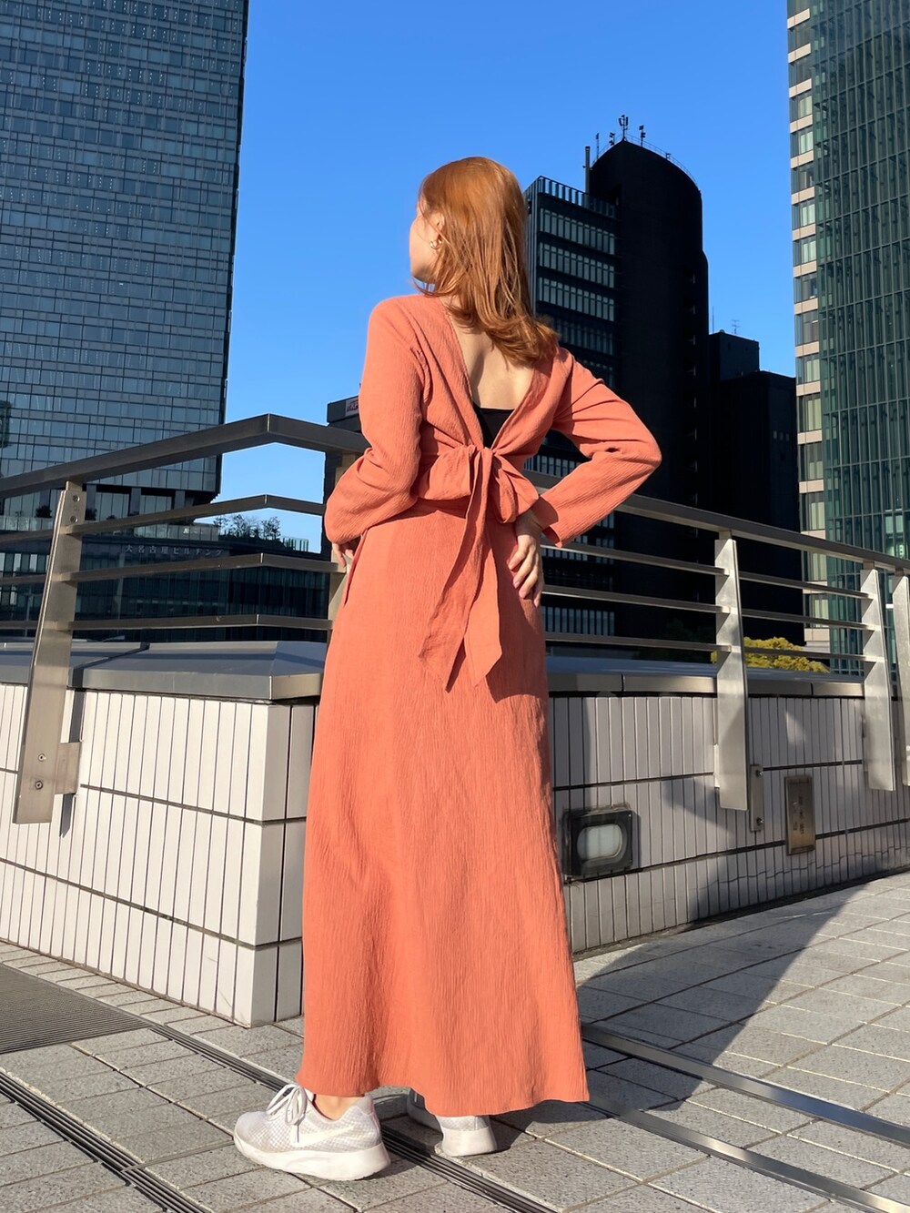 オレンジ系のワンピース、ブルー系のデニムジャケットを着用したレディースの春コーディネートの4枚目の写真