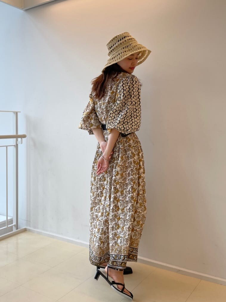 ホワイト系のワンピース、ブラック系のサンダル、ベージュ系のハットを着用したレディースの春コーディネートの4枚目の写真