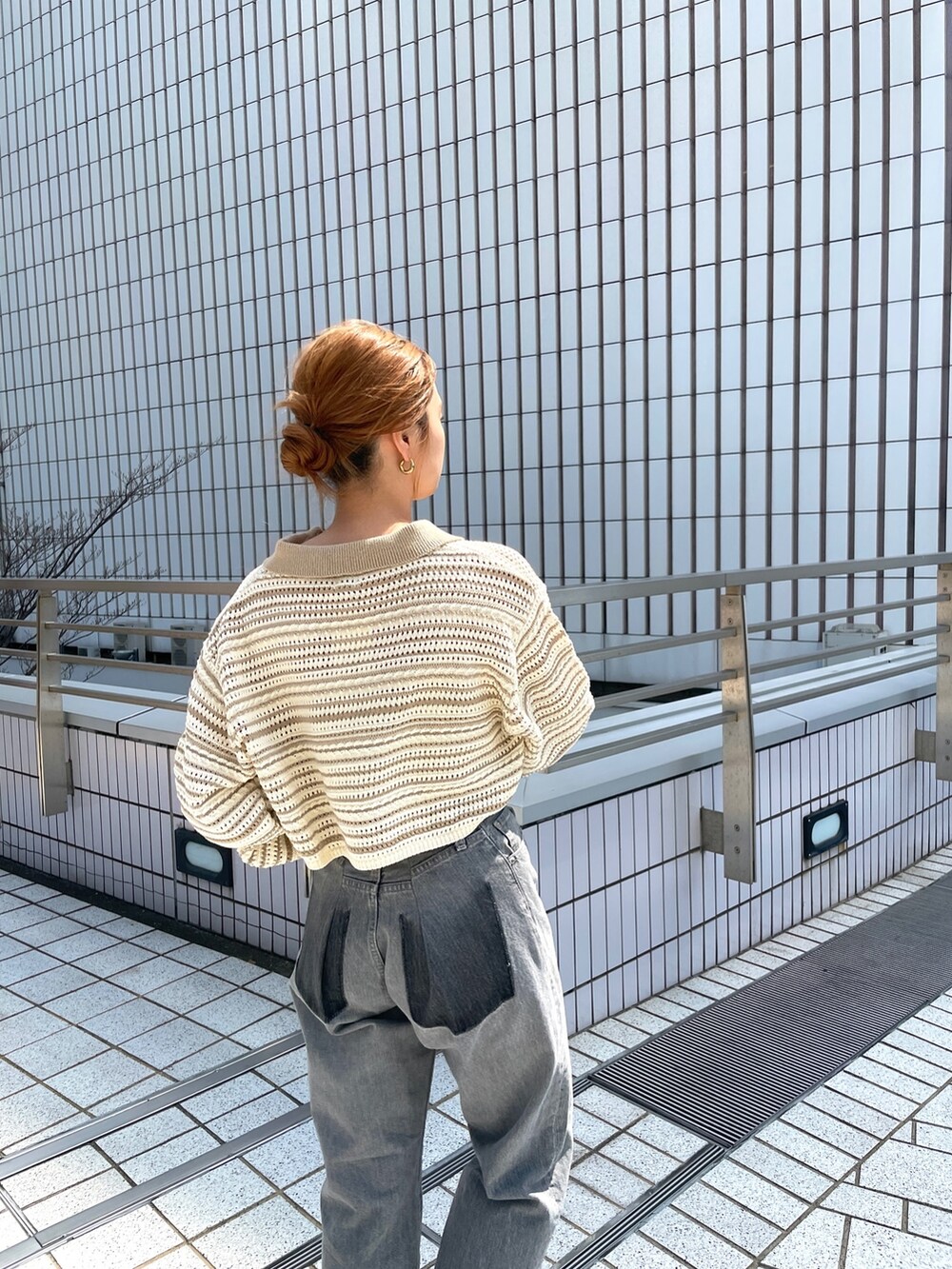 ブラック系のデニムパンツ、ベージュ系のニット/セーターを着用したレディースの春コーディネートの2枚目の写真