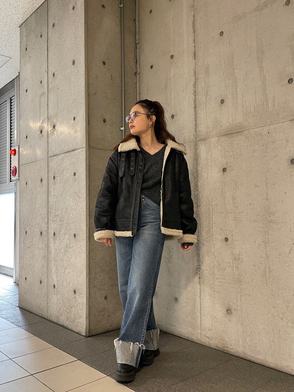 ブラック系のムートンコート、ブルー系のデニムパンツ、グレー系のニット/セーターを着用したレディースの冬コーディネートの10枚目の写真