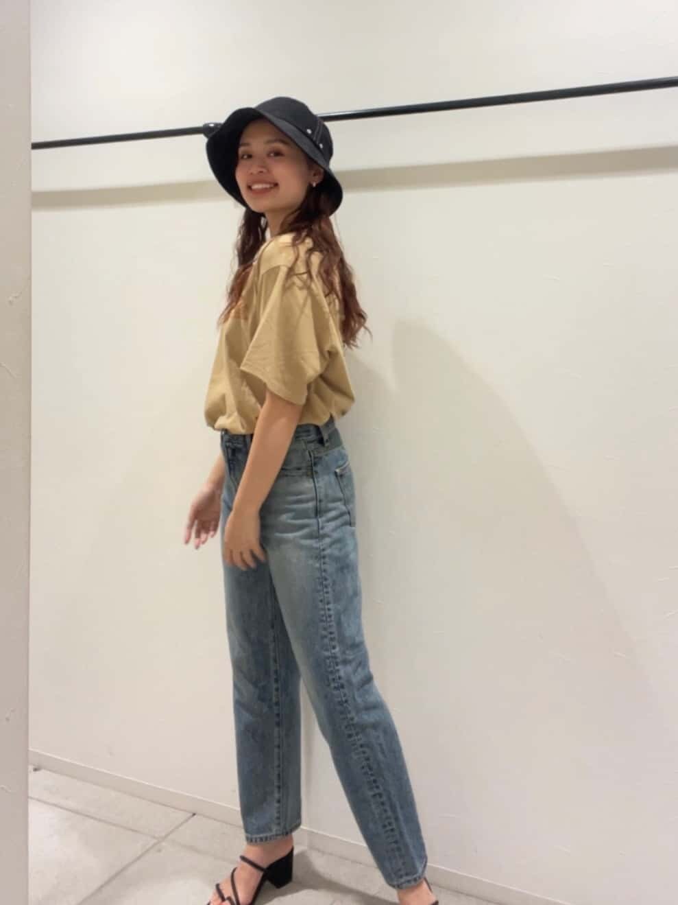 ブルー系のデニムパンツ、ブラック系のサンダル、ベージュ系のTシャツ/カットソーを着用したレディースの夏コーディネートの2枚目の写真
