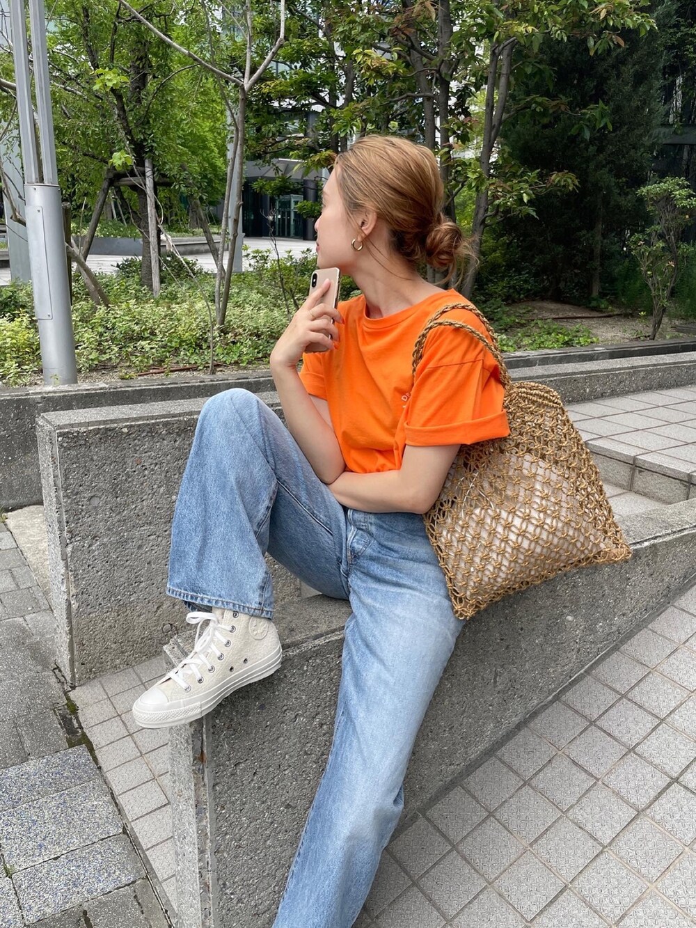 オレンジ系のTシャツ/カットソー、ブルー系のデニムパンツ、ホワイト系のスニーカーを着用したレディースの夏コーディネートの2枚目の写真