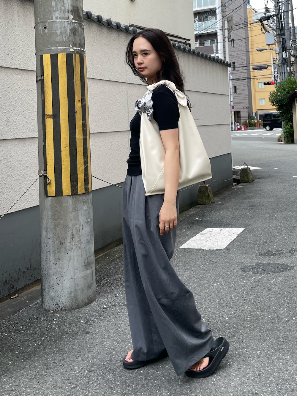 グレー系のその他パンツ、ホワイト系のハンドバッグ、ブラック系のTシャツ/カットソーを着用したレディースの夏コーディネートの2枚目の写真