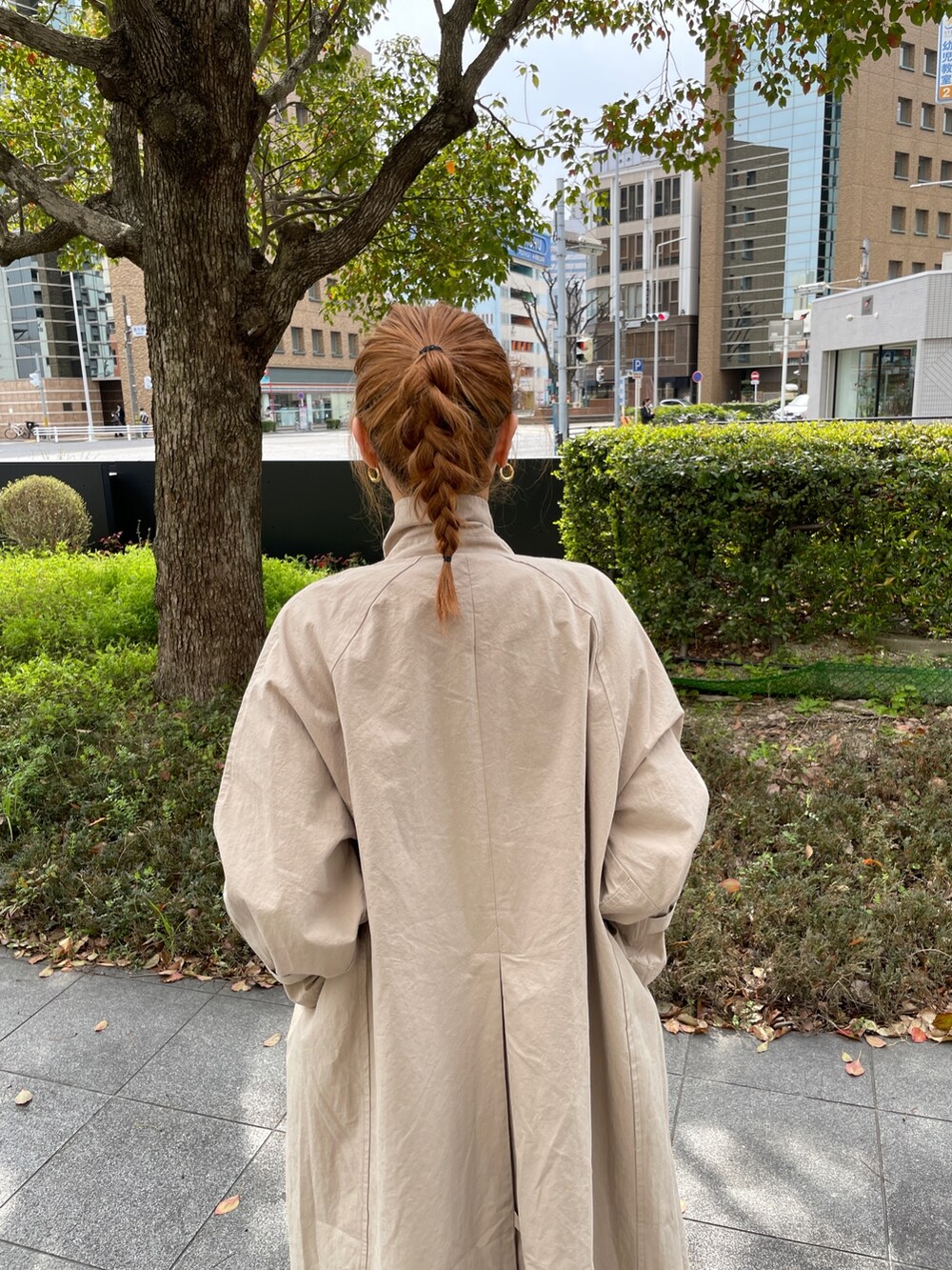 グリーン系のワンピース、ブルー系のトートバッグ、ベージュ系のステンカラーコートを着用したレディースの春コーディネートの2枚目の写真