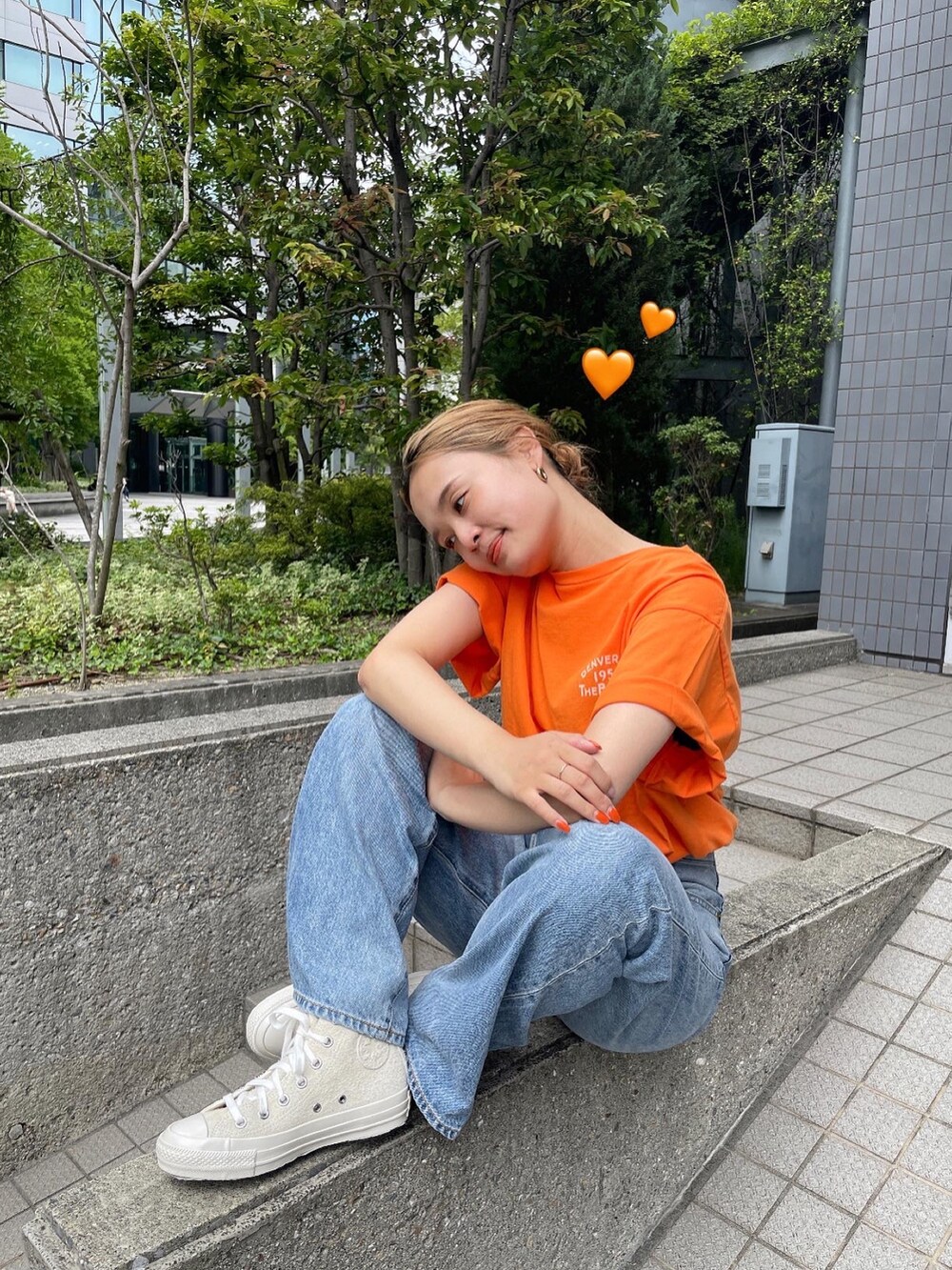 オレンジ系のTシャツ/カットソー、ブルー系のデニムパンツ、ホワイト系のスニーカーを着用したレディースの夏コーディネートの3枚目の写真