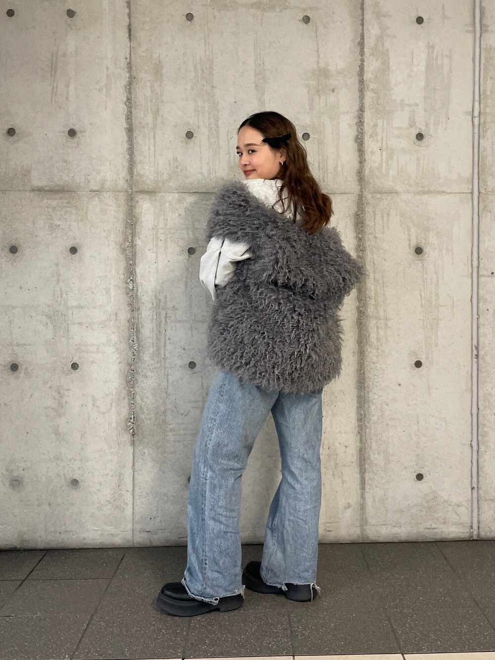 ブルー系のデニムパンツ、グレー系のスウェット、グレー系のベストを着用したレディースの冬コーディネートの4枚目の写真