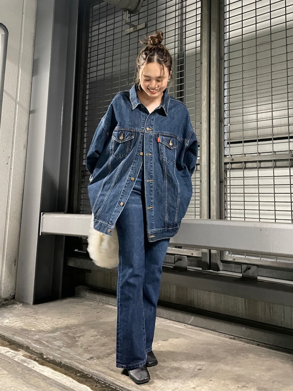 ホワイト系のショルダーバッグ、ブルー系のデニムジャケット、ブルー系のデニムパンツを着用したレディースの夏コーディネートの2枚目の写真