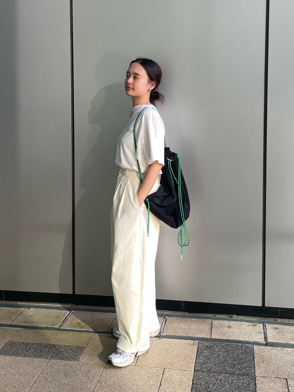 ホワイト系のTシャツ/カットソー、ホワイト系のチノパンツ、ブラック系のバックパック/リュックを着用したレディースの夏コーディネートの5枚目の写真