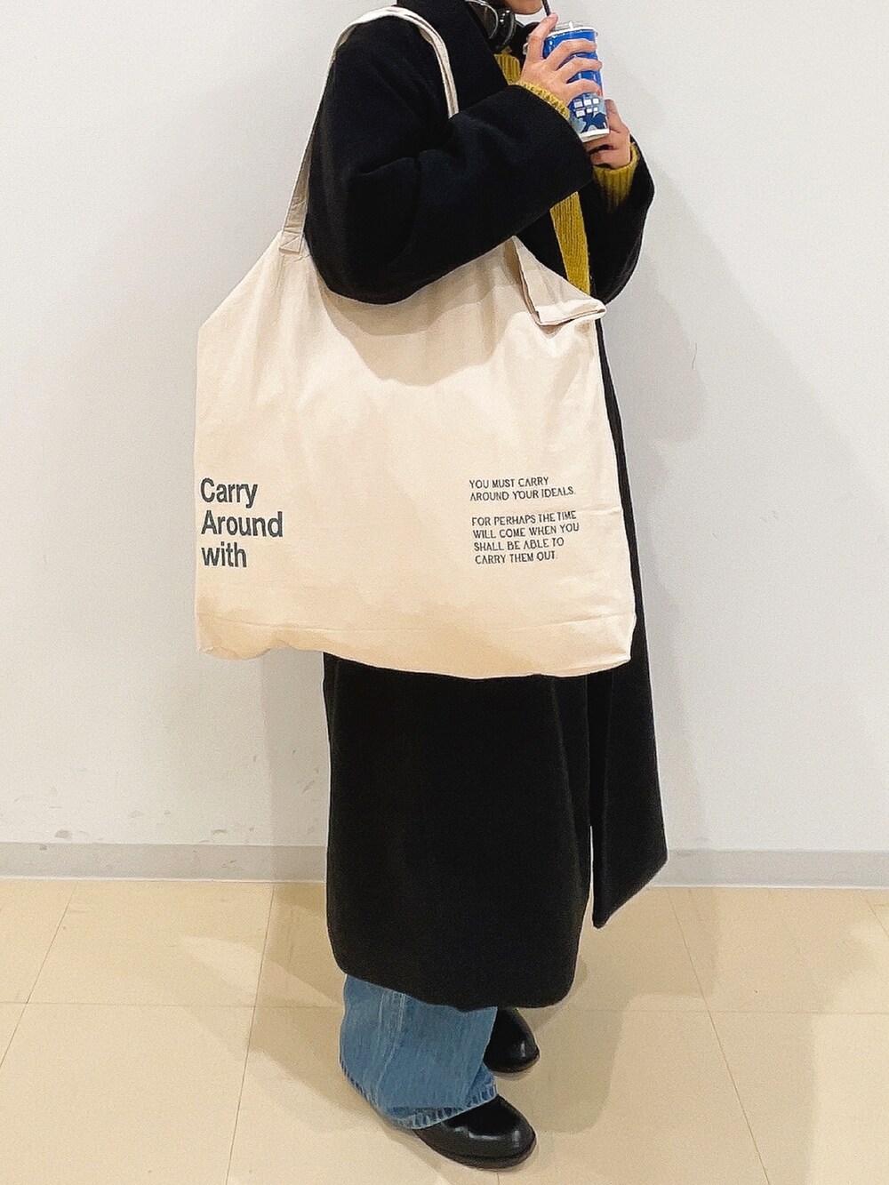 イエロー系のニット/セーター、ホワイト系のハンドバッグ、ブルー系のデニムパンツを着用したレディースの冬コーディネートの9枚目の写真