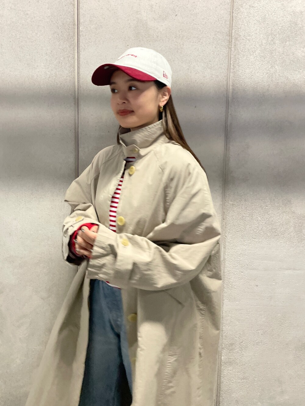 ブルー系のデニムパンツ、ベージュ系のステンカラーコート、レッド系のTシャツ/カットソーを着用したレディースの冬コーディネートの5枚目の写真