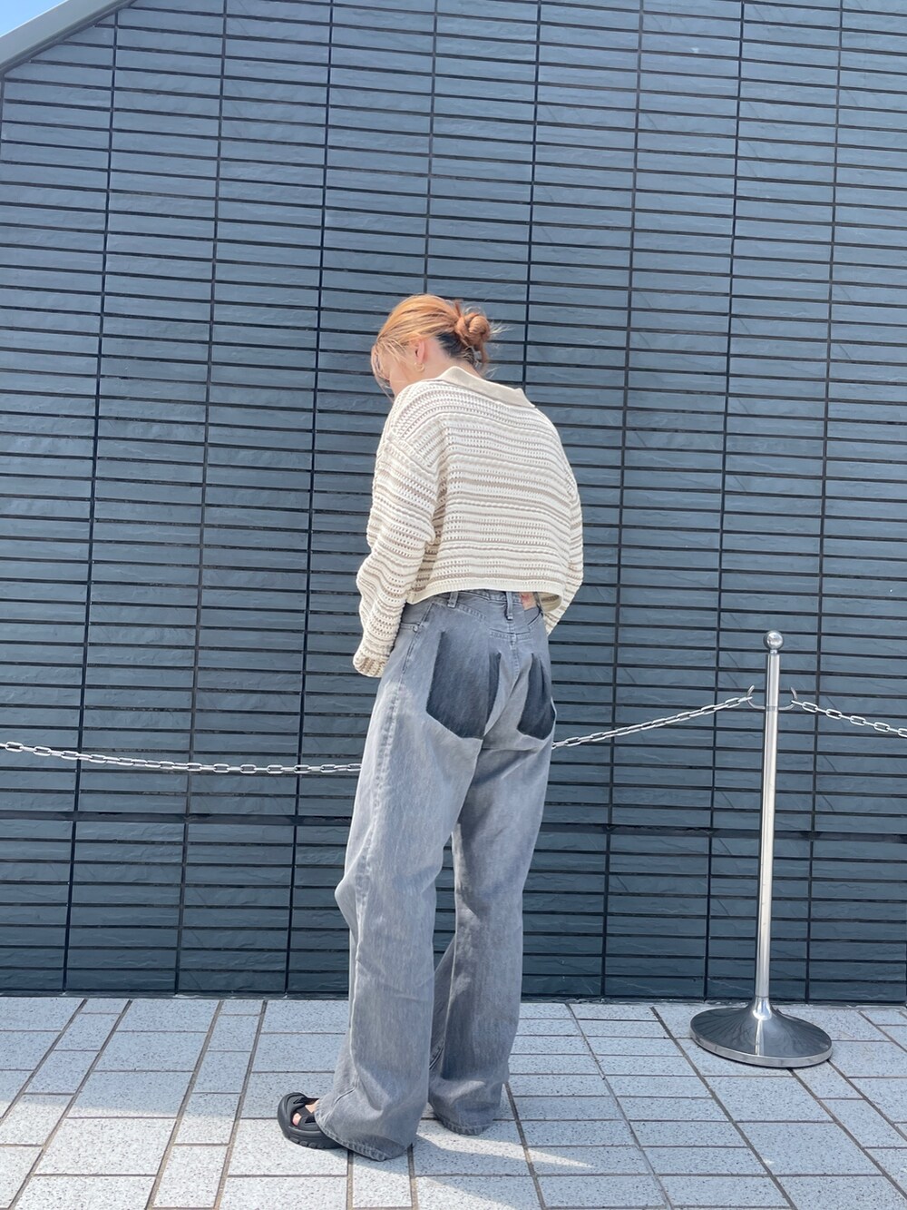 ブラック系のデニムパンツ、ベージュ系のニット/セーターを着用したレディースの春コーディネートの3枚目の写真