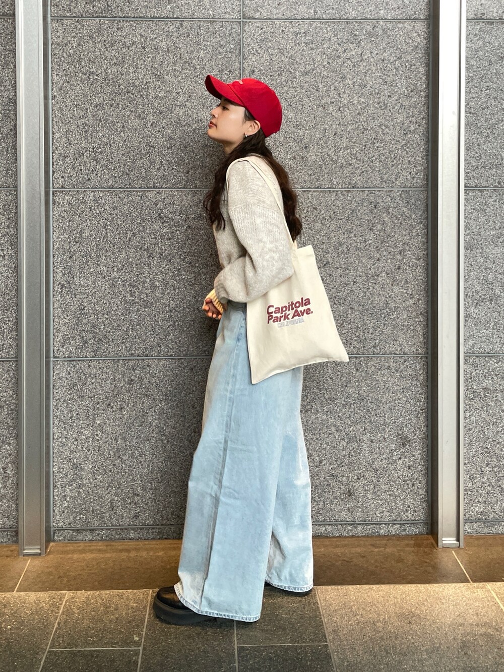 ブルー系のデニムパンツ、ホワイト系のニット/セーター、レッド系のトートバッグを着用したレディースの秋コーディネートの2枚目の写真