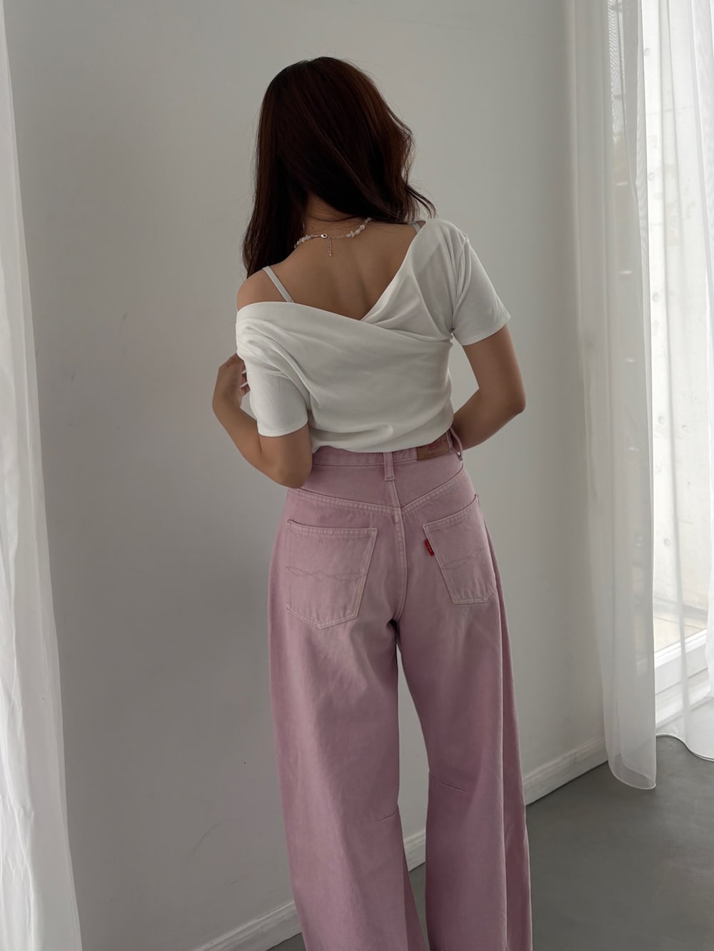 ピンク系のデニムパンツ、ブルー系のハンドバッグ、ホワイト系のTシャツ/カットソーを着用したレディースの春コーディネートの2枚目の写真