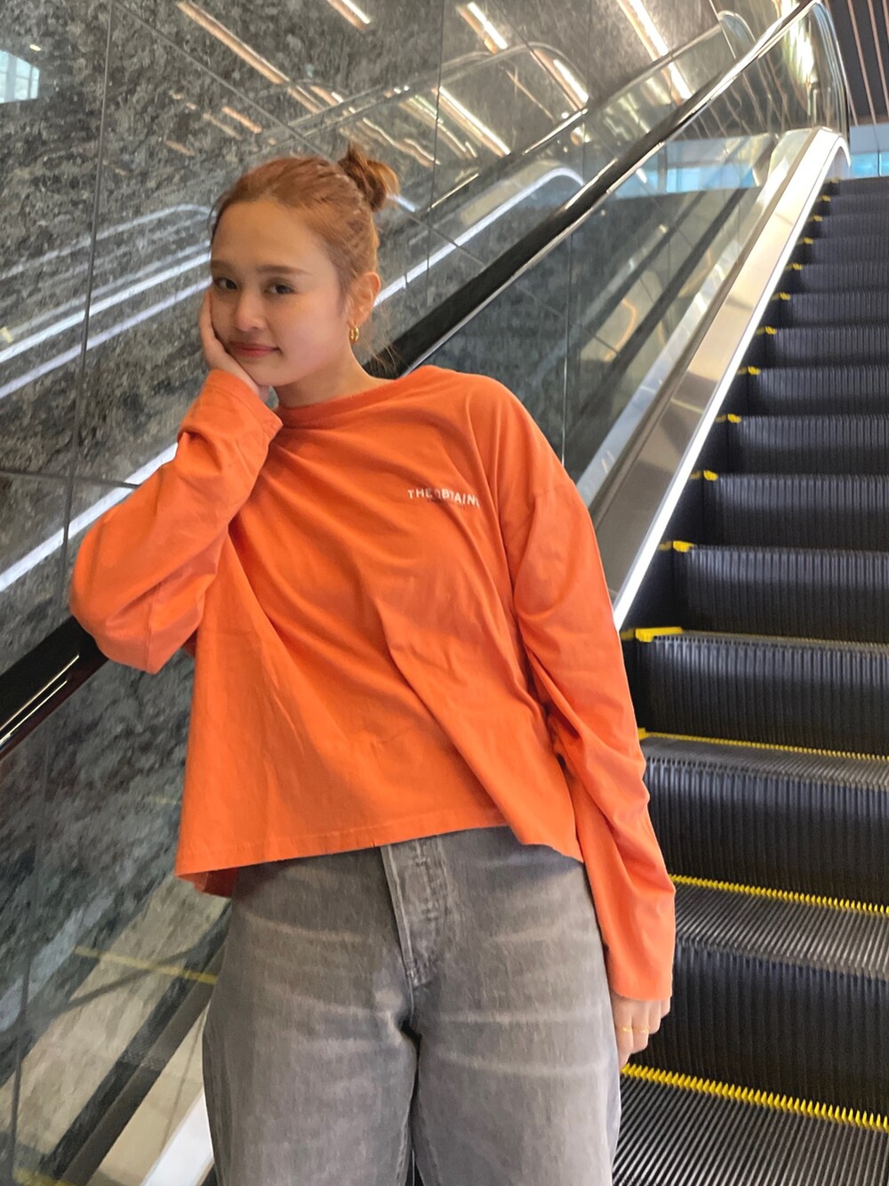 ブラック系のデニムパンツ、オレンジ系のTシャツ/カットソーを着用したレディースの冬コーディネートの5枚目の写真